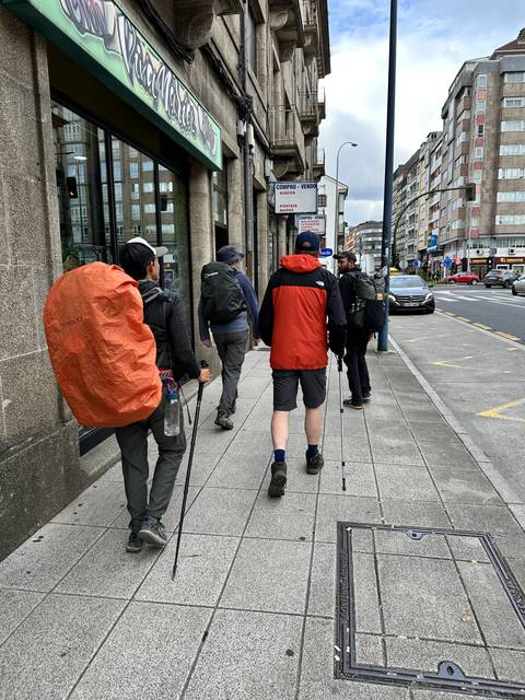 Walkers heading out of town, packs on, early.